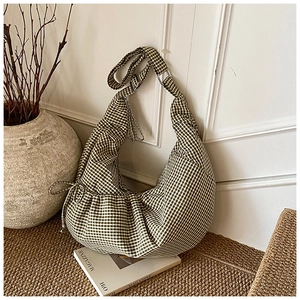 Detail of green and white gingham dumpling bag with side drawstring and ruched texture