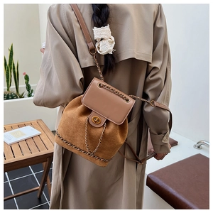 Rear view of a model wearing a brown vintage bucket backpack with suede and chain detail