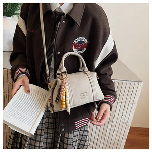 Detail of off-white Boston bag with decorative colorful beads and embossed lettering