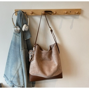 Detail of vintage brown suede tote bag featuring contrast leather trim and a pompom charm