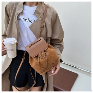 Detail view of brown suede and leather bucket backpack with gold clasp on model