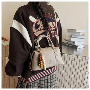 Retro beige Boston bag detail with wooden bead charm and embossed letter pattern