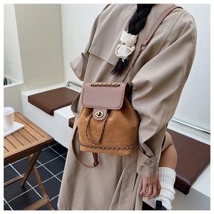 Detail of suede bucket backpack featuring retro metal chain and secure turn-lock closure