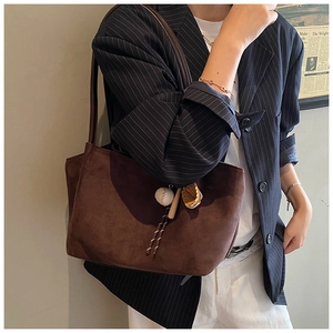 Detalle de bolso tote de ante con colgantes de béisbol y correas de hombro de cuero