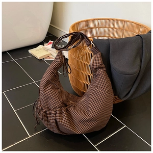 Detailed view of large checkered moon bag with drawstring detail on a cozy home background