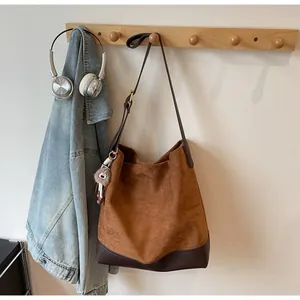 Close-up of a vintage brown suede tote bag with leather straps on a wooden hanger