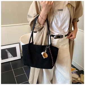 Primer plano del bolso tote de ante negro con colgante de guante de béisbol y cinta