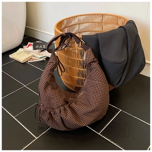 Detail of checkered hobo bag with zip closure and side drawstring in a cozy setting