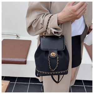 Detail of a black mini suede backpack featuring a gold turn-lock and metallic chain strap