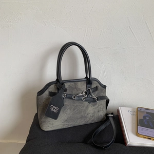 Detail of grey-green vintage handbag featuring black leather handles and metal eyelets