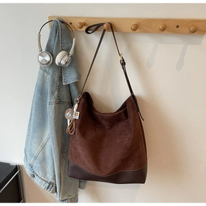Detail shot of a dark brown vintage bucket bag with plush charm on a wooden wall rack