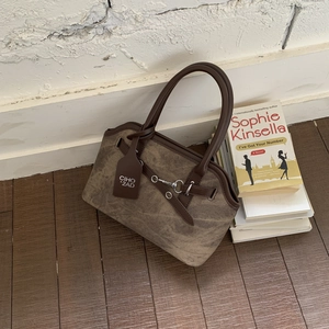 Detail shot of vintage brown satchel with silver buckle and leather handle on a wooden floor
