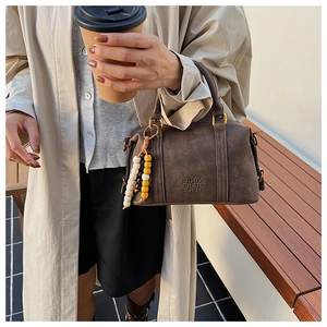 Detail of dark brown vintage Boston bag with wooden bead tassel and engraved text