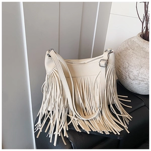 Gros plan du sac seau à franges crème avec texture cuir grainé et détails de glands