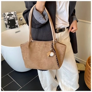 Bolso tote de ante marrón con correas de cuero y colgantes de béisbol al hombro