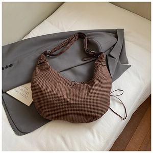 Detail of checkered crescent bag with adjustable wide strap on a soft cushion