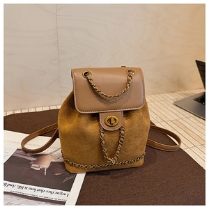 Close-up of mustard yellow suede backpack with brown leather flap and golden chain detail