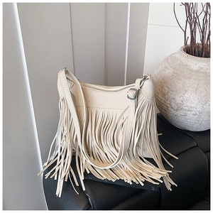 Détail d'un sac seau en cuir beige avec de longues franges et une bandoulière réglable