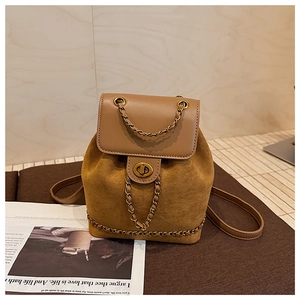 Detailed macro view of brown suede bucket bag with gold chain and metal twist lock