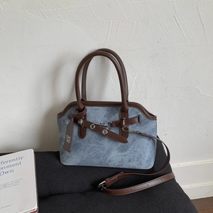 Detail of vintage gray-blue crossbody bag with brown leather trim and metal clasp