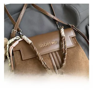 Detail view of brown patchwork leather bag with woven handle and gold brand embroidery