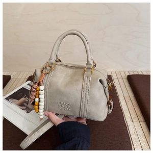 Detail of light gray crossbody bag with decorative bead chain and gold-tone metal hardware