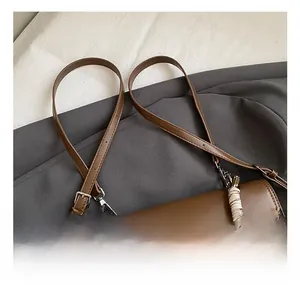 Detail view of the adjustable leather strap and embossed heart pattern on the retro brown bag