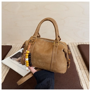 Detail of mocha brown Boston bag showing embossed logo and colorful beaded keychain