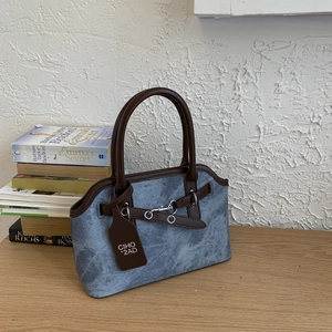 Detail of vintage washed denim handbag with brown leather handles and metallic buckle