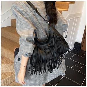 Détail d'un sac seau vintage en cuir noir avec de longues franges et texture grainée