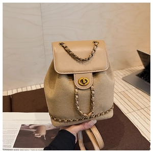 Detail of khaki suede backpack with leather flap and golden twist lock on wooden desk