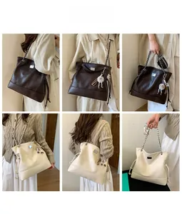 Detail view of large tote bag with leather texture, chain straps and plush charm accessory