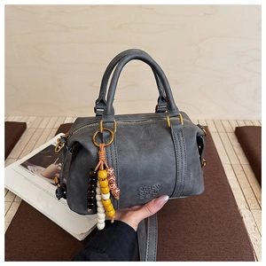 Detail of gray leather Boston bag with vintage gold hardware and bead tassel charm