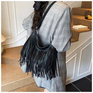 Détail du sac hobo en cuir noir avec franges bohèmes et une large bandoulière ajustable