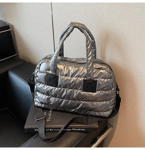 Détail du sac fourre-tout matelassé argenté avec bandoulière noire et zip métallique