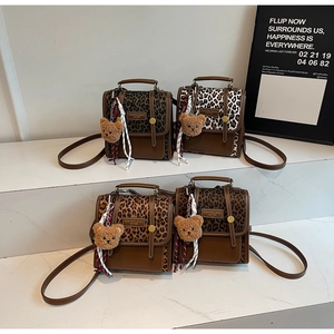 Close-up of stylish leopard print crossbody bags with cute bear charm and woven rope detail