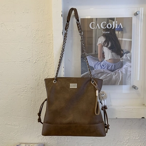 Gros plan d'un sac cabas vintage marron foncé avec bandoulière et pendentif peluche