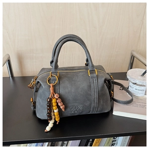 Grey vintage Boston bag detail with bronze hardware and colorful bead accessory
