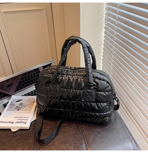 Gros plan sur le sac matelassé noir en nylon avec sa bandoulière en tissu réglable