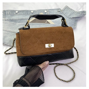 Detail of quilted diamond pattern and golden twist lock on two-tone crossbody bag