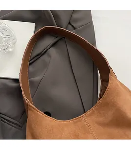 Detail of a brown suede tote with wide leather shoulder strap and reinforced stitching