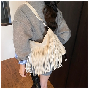 Détail d'un sac à bandoulière crème à franges avec texture fluide et sangle réglable