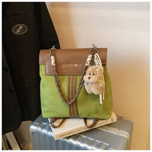 Detail of green suede backpack with dark brown leather flap and cute teddy bear charm