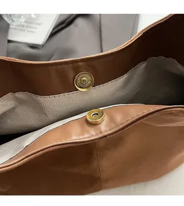 Close-up of premium gold magnetic clasps and herringbone lining in a brown suede handbag