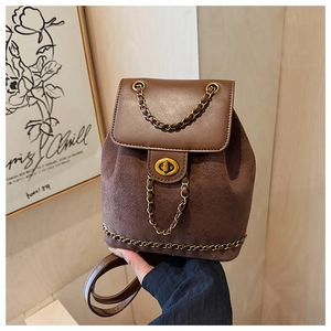Detail of dark brown bucket backpack featuring gold chain strap and turn-lock closure
