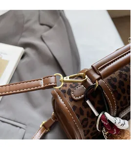 Detail of leopard print cylinder bag featuring gold hardware and stylish braided charm