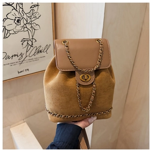 Detail of tan suede and leather backpack featuring golden chain straps and turn-lock