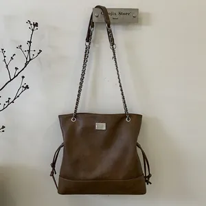 Détail du sac cabas vintage marron avec bandoulière en chaîne et accents de cordon latéral