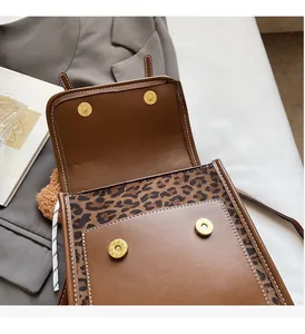 Detailed view of brown leather bag featuring leopard print texture and gold magnetic snaps