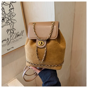 Detail of vintage suede bucket backpack featuring gold chain straps and twist lock closure